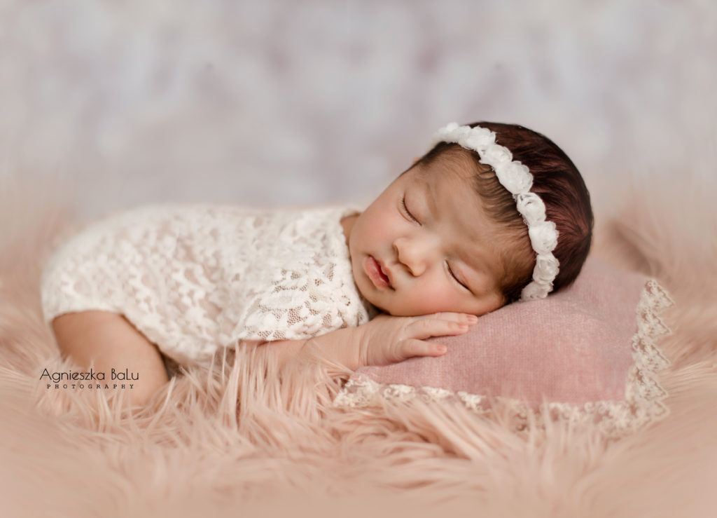 Das Neugeborene hält die Beinen under dem Popo die Händen unter dem Kopft und schläft geborenen auf die Rosadecke.