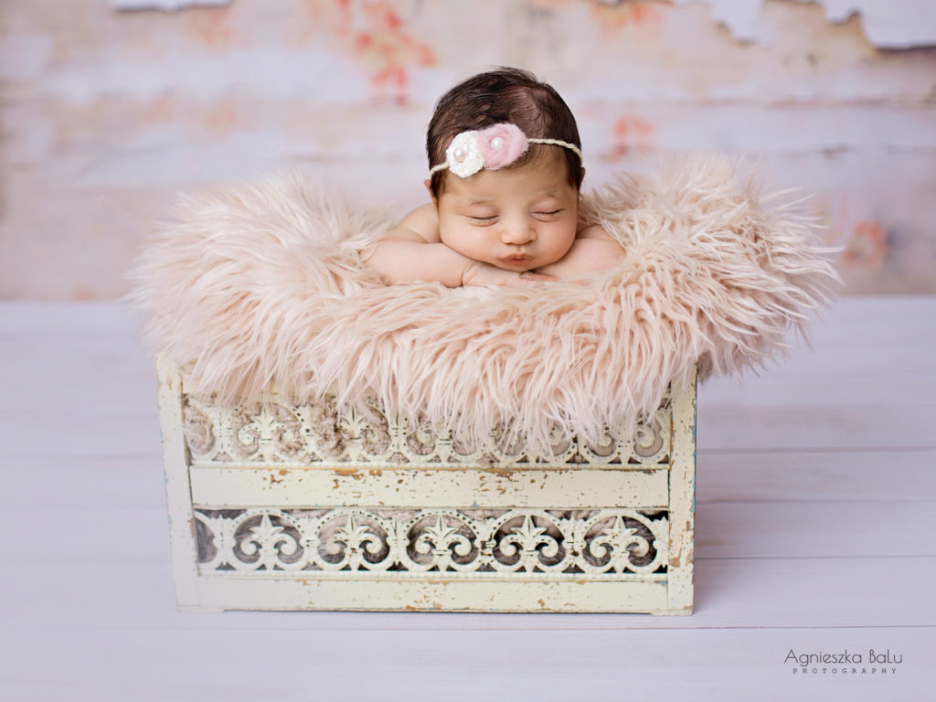 Die Neugeborenenfotografie von dem kleinen Mädchen die in einen Bohoeimer liegt und schläft. Die Pastelfarben passen sehr gut zu dem Babymädchen.