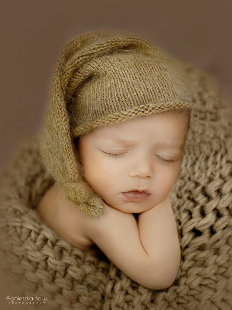 Das Baby trägt eine Schafmütze. Die braune Decke und braune Mütze sehen sehr schön aus.